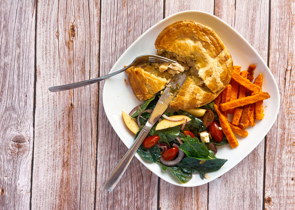 Serving suggestion. A plate with spinach salad with a hot pie and sweet potato fries