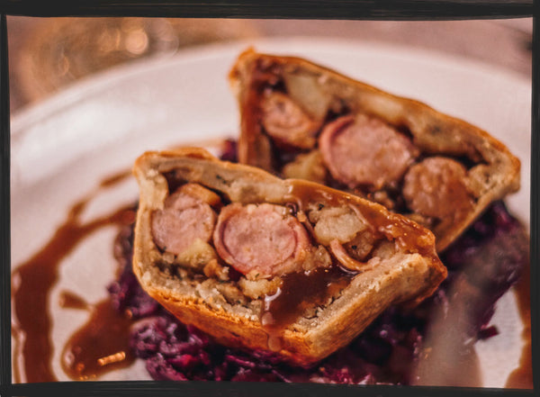 Piggin' awesome pigs in blanket pie served on a white plate with gravy