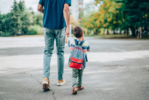 Modern motherhood, back to school, holding dads hand walking into school