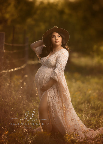 modèle enceinte pose à l'extérieur vêtue d'une longue robe en dentelle