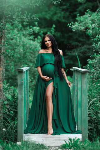 Brünettes schwangeres Model posiert draußen und trägt ein grünes Kleid