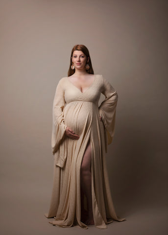 This pregnant model is wearing a long dress. The dress has a Boho style and is perfect for all your photoshoots. The dress is made from a stretchy material and has flowy sleeves. 