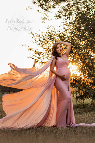 Schwangeres Model posiert im Freien mit einem rosa langen Kleid