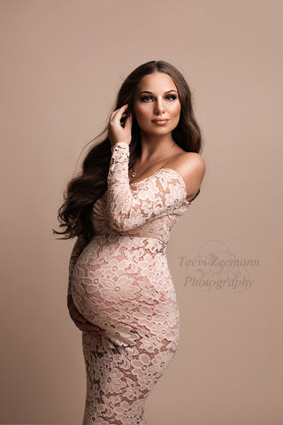 pregnant model poses in a studio wearing a pink lace dress