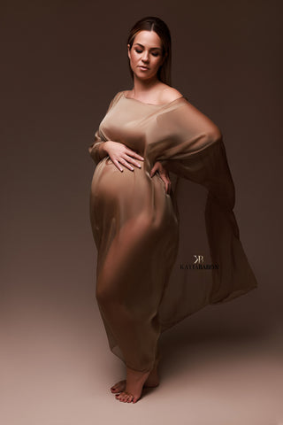 brunette pregnant model poses in a studio wearing an espresso coloured maternity cape in voile fabric. 