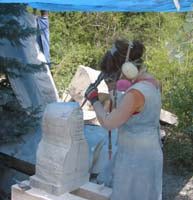Artist Kelly Borsheim uses a pneumatic hammer to chip away at her marble sculpture of a female torso.
