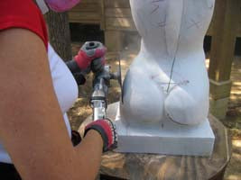 Back in her studio in Texas, sculptor Kelly Borsheim trims the left hip of the female torso with a diamond disc blade.
