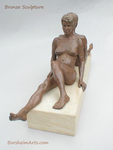 a different view of the seated pregnant woman bronze sculpture showing one leg stretching out in front of her. art by Kelly Borsheim