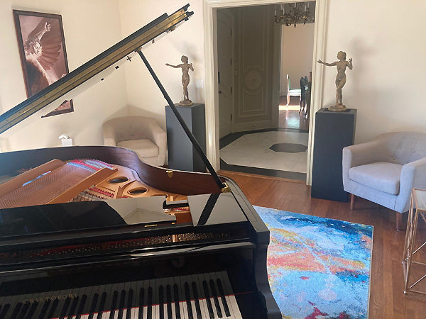 The Triumph of Icarus and bronze Mermaid sculptures in a room with a piano