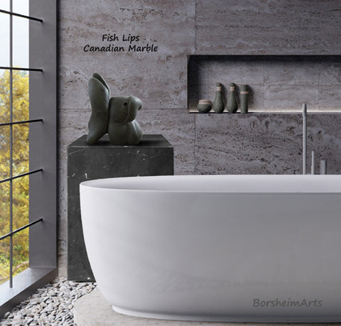 Fish Lips contemporary marble sculpture is shown in this elegant bathroom with large white tub and grey travertine stone walls. 