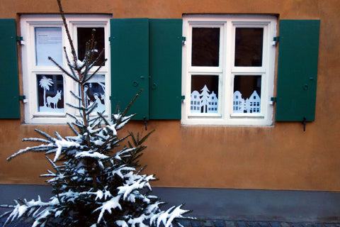 windows decorated with white paper cutout designs of houses and nativity scenes, Augsburg Bavaria Germany Fuggerei