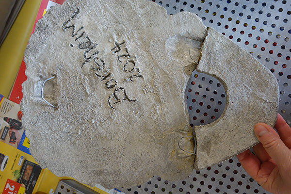 Casting concrete, upper portion of face with artist Kelly Borsheim's signature on the back of the wall art