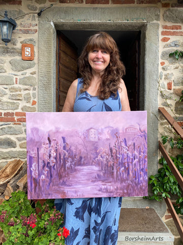 Artist Kelly Borsheim holds up her new oil painting Vineyard in Fog, Montecarlo Tuscany, photo by Jane Sulicich
