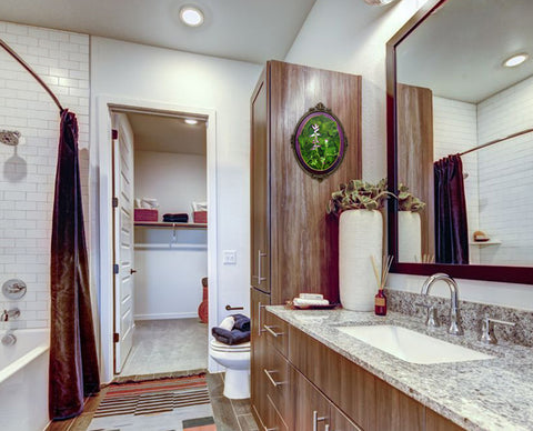 A closeup trompe l'oiel painting of wildflower with English Ivy in an antique Italian oval frame hangs in this bathroom in an apartment rental in Austin, Texas, lovers of green