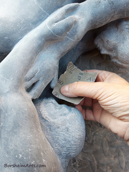 hand using sandpaper to polish stone sculpture