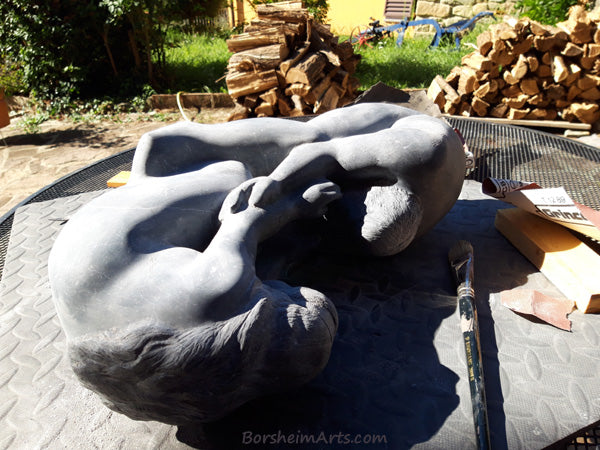 Sculpture lying on side in bright sun.  showing the soft shapes of shadow edges Helping Hands