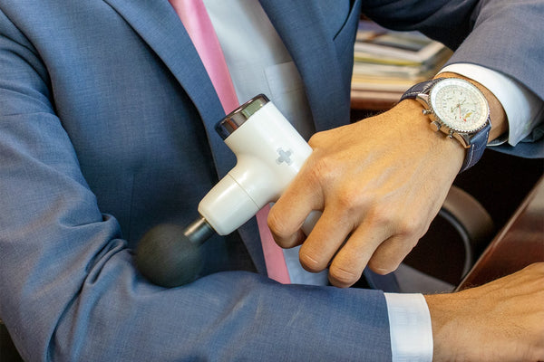 Man using massage gun on arm.