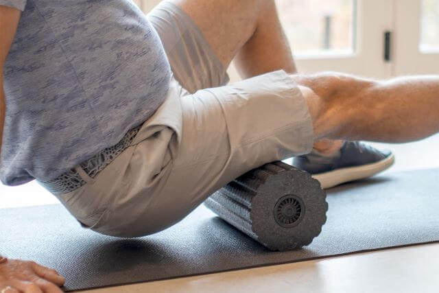 Man using a foam roller on hamstrings.