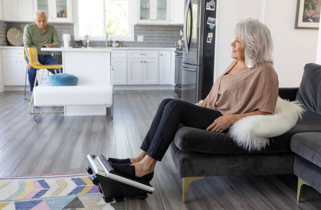 Femme utilisant un masseur de pieds oscillant tout en se relaxant à la maison.