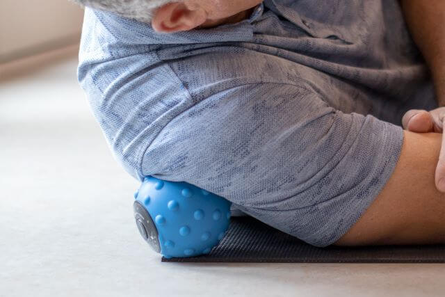 Hombre usando pelota de masaje en los músculos del hombro.