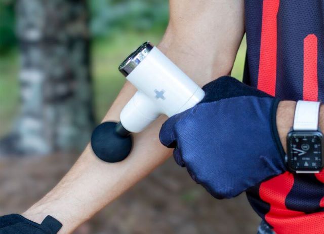 Person using massage gun on arm muscles.