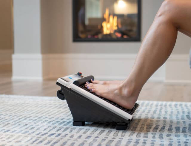 Person resting feet on vibrating foot massager.