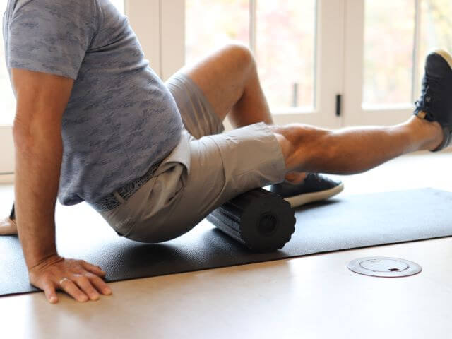 Man using foam roller on hamstrings.