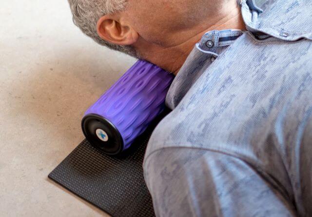 Man using foam roller on upper back and neck area.