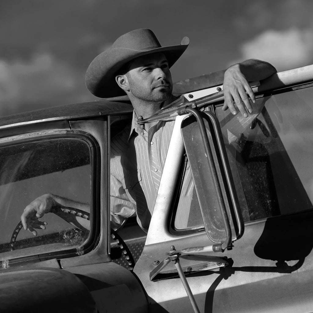 Bruce Dorn model wearing cowboy hat standing at truck inside driver door hand on steering wheel and arm resting on top of door