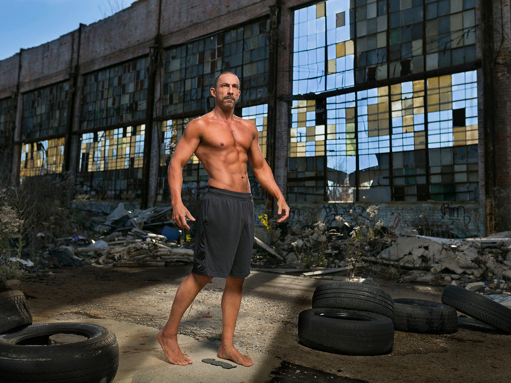 James Schmelzer Atheletic man wearing shorts in old tire yard