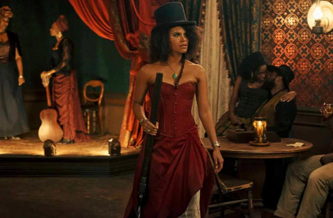 Stagecoach Mary, played by Zazie Beetz, in a black top hat, and dark red corset and skirt