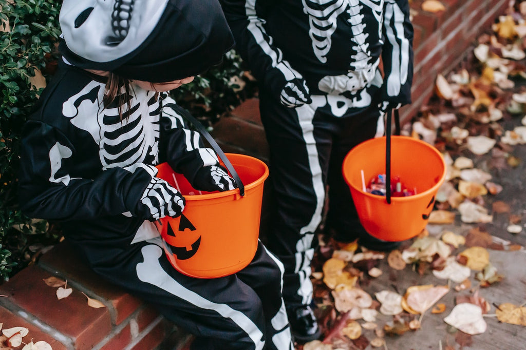 two children in halloween costumes with trick or treat buckets