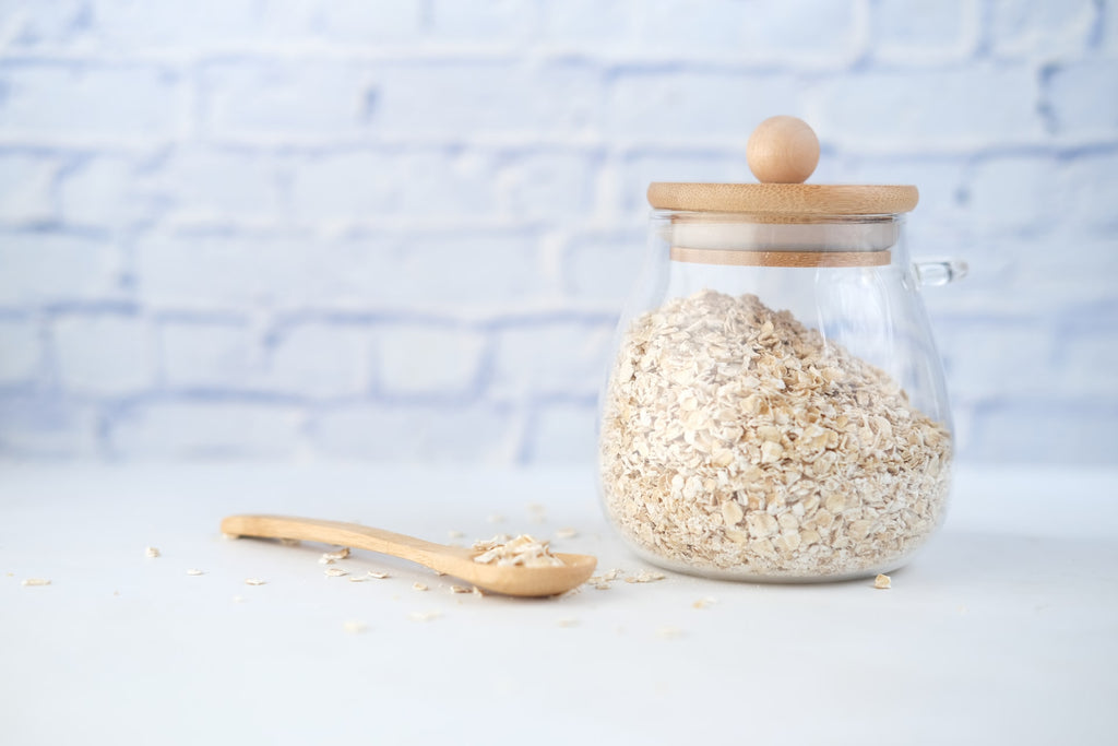glass jar of oats with a wooden spoon on a white worktop