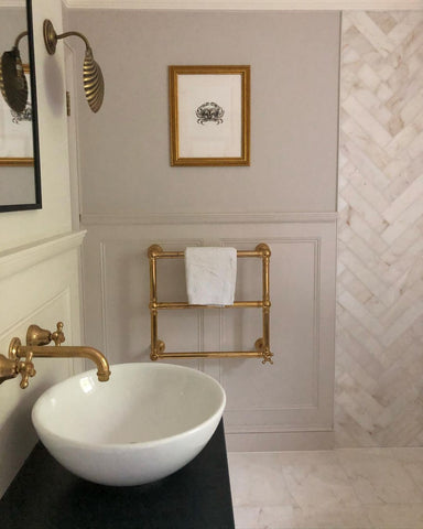 Brass heated towel rail in neutral country bathroom