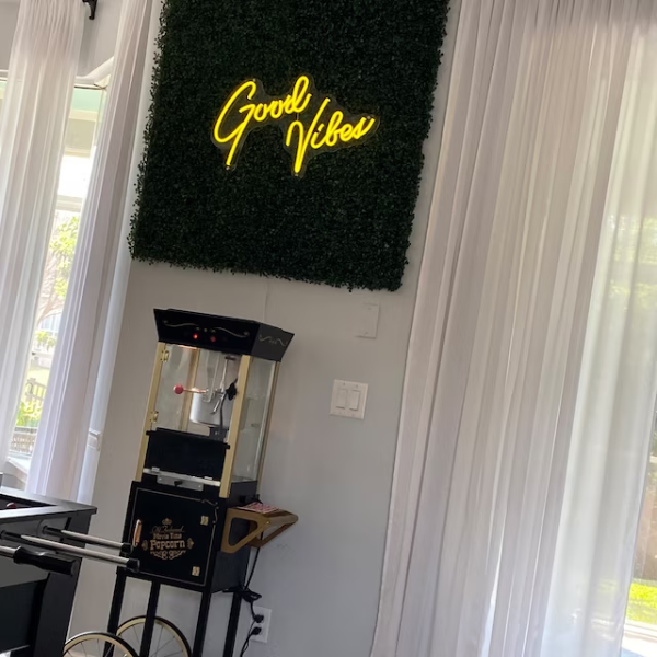 Yellow Good Vibes neon sign in living room above popcorn machine