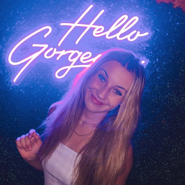 Girl posing in front of purple Hello Goregous neon sign