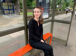 Woman at bus shelter with hero mask on