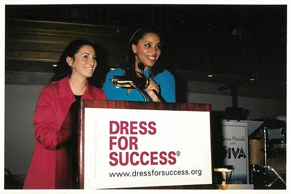 Two women standing at podium accepting award behind sign that says 