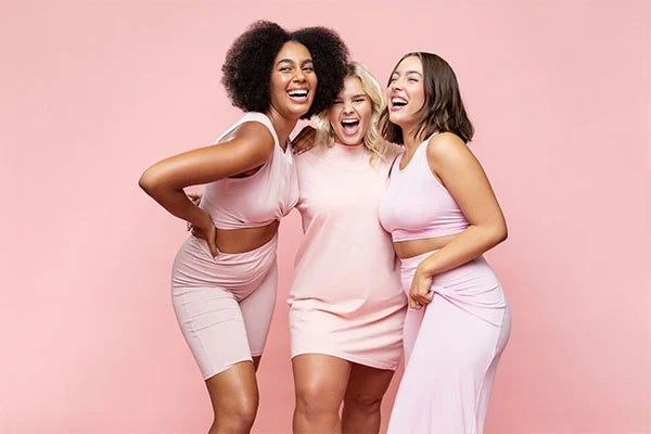 Three women smiling wearing pink summery loungewear against pink background