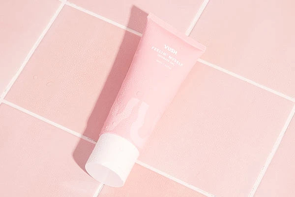 Pink bottle of water-based lube with white lid against pink bathroom tiles