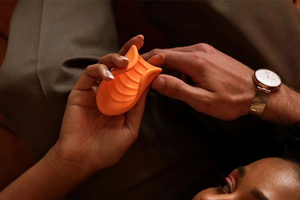 Couple's hands holding VUSH Sol orange ribbed vibrating stroker