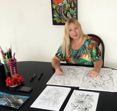 Irina Velman, a NZ artist. Irina is sitting at a large table drawing.