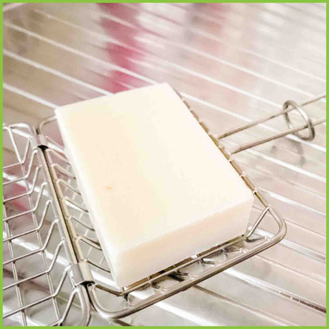 A bar of dish soap sitting in an open dish soap cage,