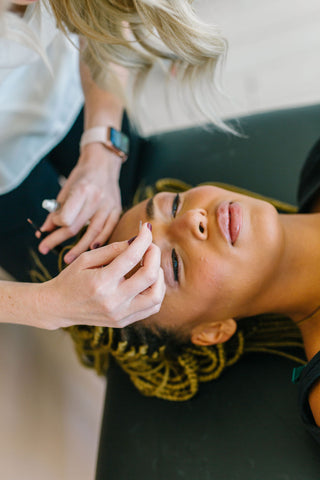 Aerial view of a woman performing a brow lamination on a client.