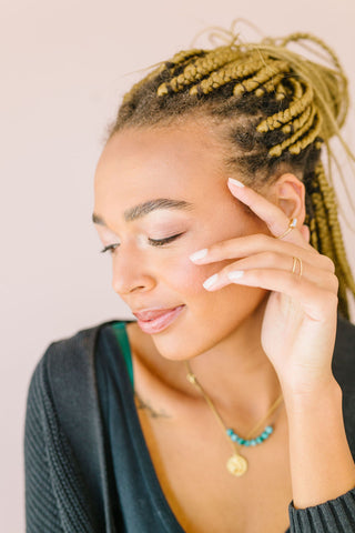 Woman with her hand on her face showing off her brow lamination.