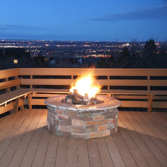 Built in fire pit on decking with fire burning and city lights in view 