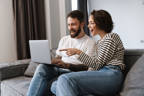 couple sitting on a couch looking at rings on lap top