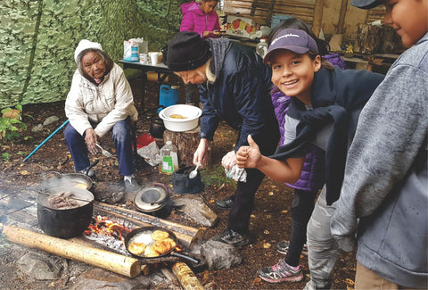 Indigenous youth cooking with Elders outside