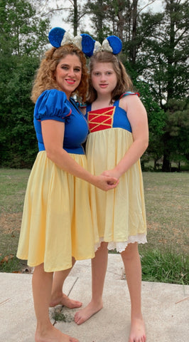 Mother and daughter wearing Snow White inspired dresses embracing. 
