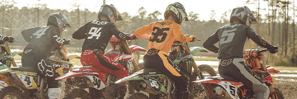 four motocross riders pulling away from the starting gate